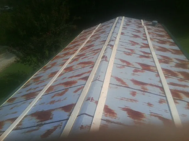 Rusted metal roof panels with new wood purlins before replacement in Manchester