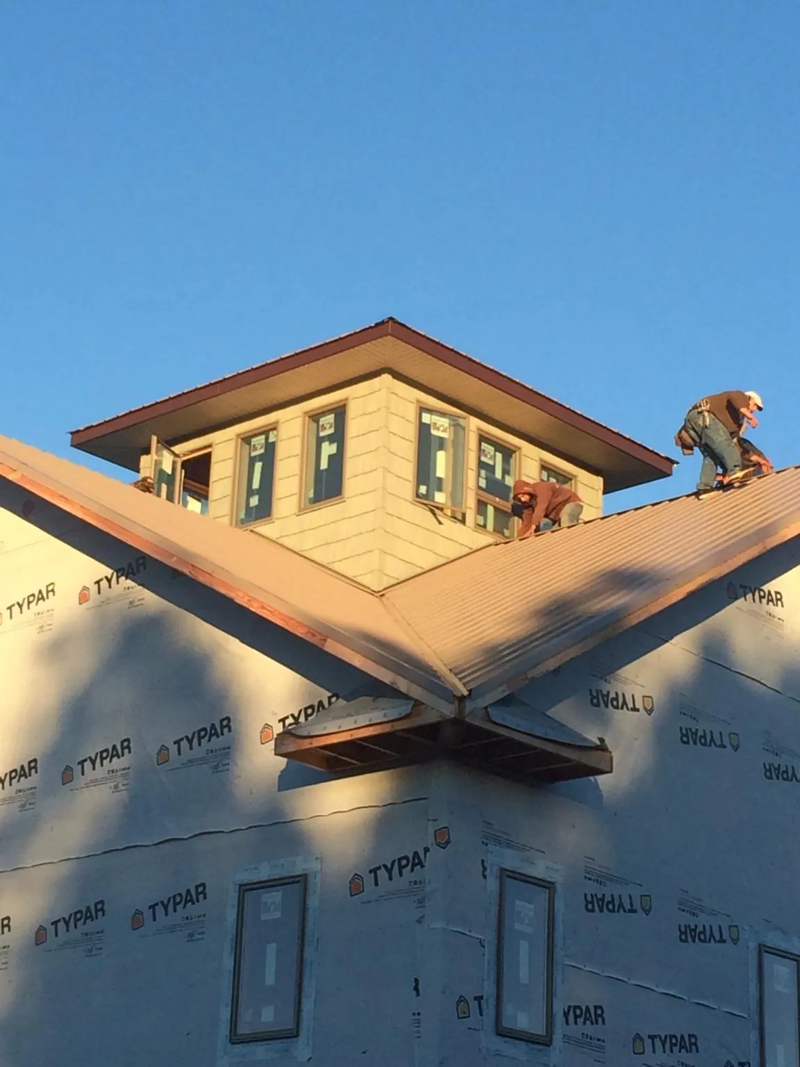Roofers working around a rooftop cupola on a new metal roof at sunset — Roof Waterproofing in Manchester by Roofing Brothers
